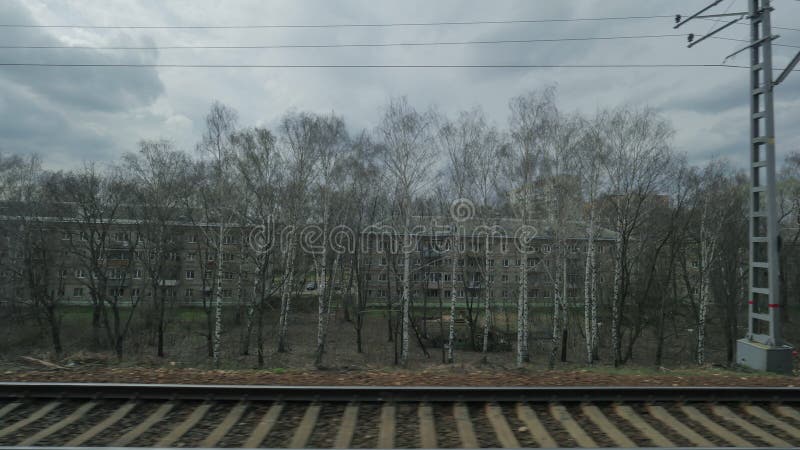 Ansicht vom Fenster von ein beweglicher Zug gesehenen Bäumen, von Gebäuden, von Brücken und von Eisenbahn