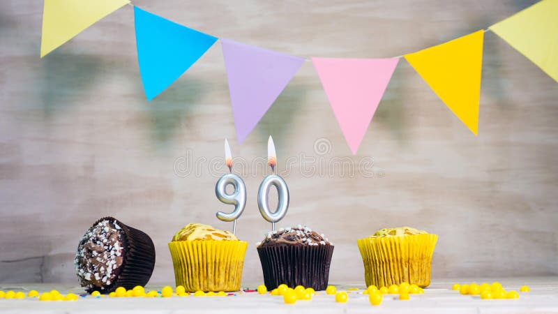 Birthday background with number 90. Beautiful birthday card with colorful garlands, a muffin with a candle burning copyspace. Birthday background with number 90. Beautiful birthday card with colorful garlands, a muffin with a candle burning copyspace