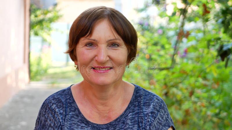 Antecedentes de una anciana sonriendo en plantas verdes