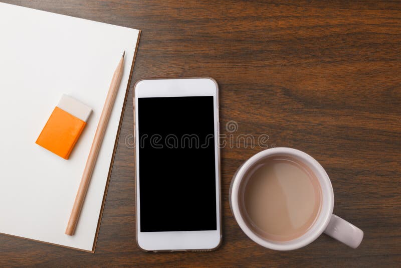 Anteckningsbok, blyertspenna, radergummi, telefon och varm drink på träskrivbordet royaltyfri fotografi Anteckningsbok, blyertspenna, radergummi, telefon och varm drink på träskrivbordet royaltyfri fotografi