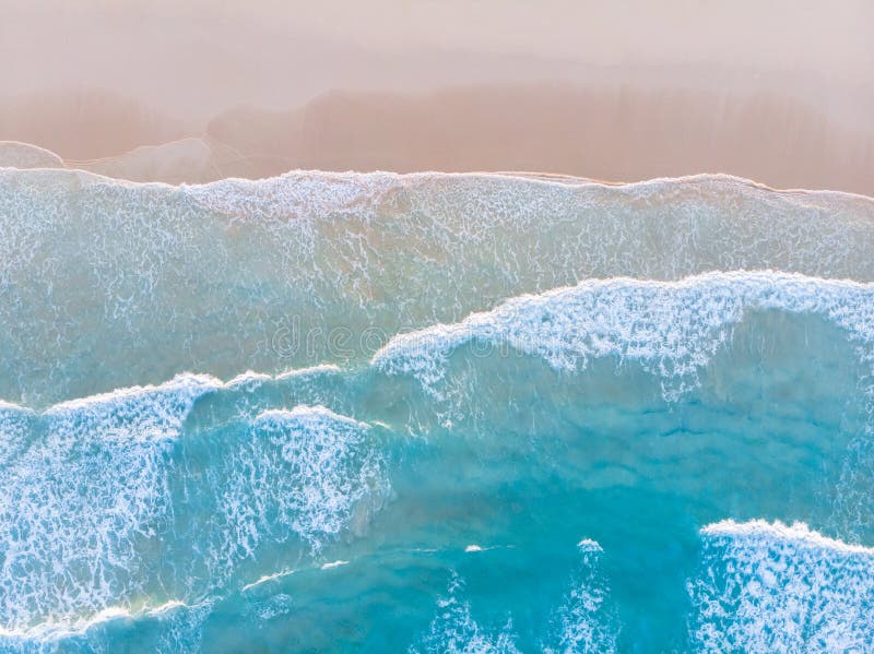 Antena de praia oceânica vista de cima para baixo com ondas de água azul com espuma e spray e belas férias de verão de areia fina Antena de praia oceânica vista de cima para baixo com ondas de água azul com espuma e spray e belas férias de verão de areia fina