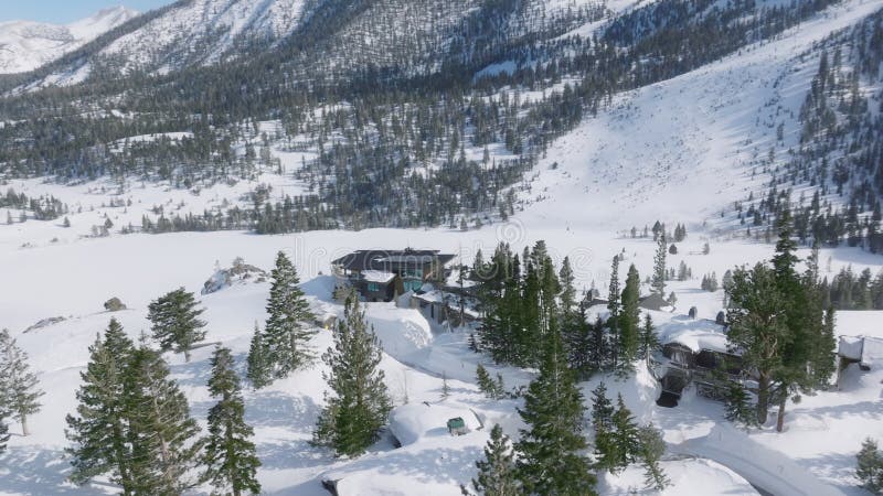 Antena épica sobre una gran casa de chalé de lujo en lo alto de una colina nevada en las montañas 4k