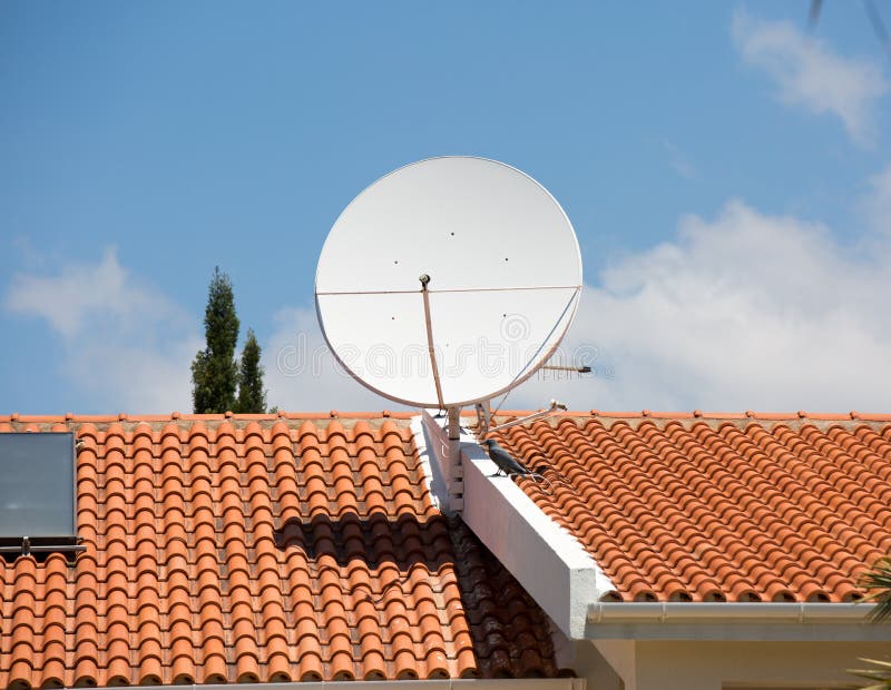 Antenna della TV sul tetto di mattonelle rosse fotografia stock Antenna della TV sul tetto di mattonelle rosse fotografia stock