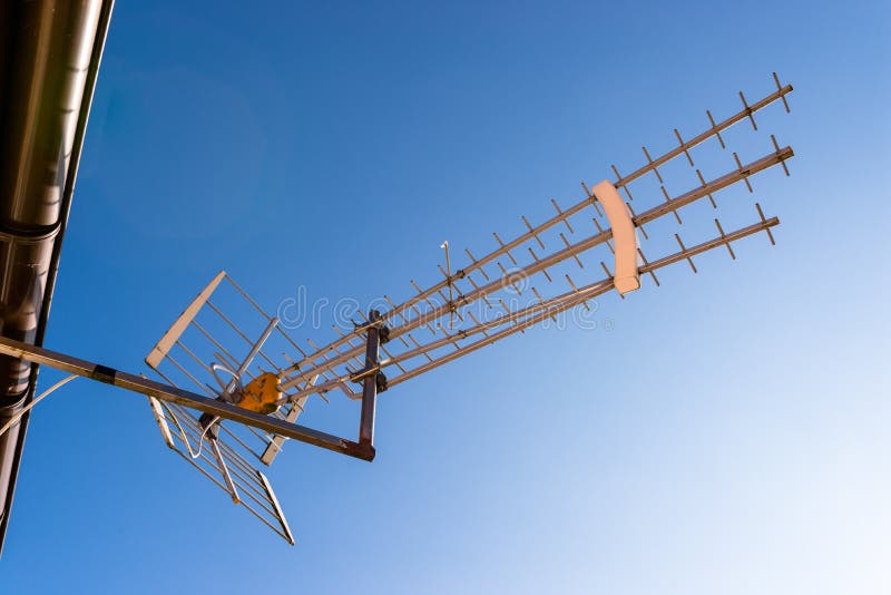 Antenna for TV receiver attached to the facade of the house against the blue sky.