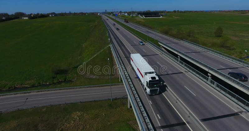 ANTENNE: Vrachtvrachtwagen die ladingscontainer op een weg vervoeren