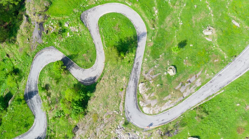 Antenne: übersteigen Sie hinunter Ansicht Tailspin über Wicklungsgebirgsstraße auf den italienischen Alpen, grünen der Wiese der stockbild Antenne: übersteigen Sie hinunter Ansicht Tailspin über Wicklungsgebirgsstraße auf den italienischen Alpen, grünen der Wiese der stockbild