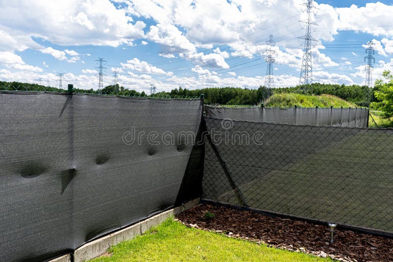 Anthracite-colored masking net placed on a mesh fence, visible pine bark under the fence.