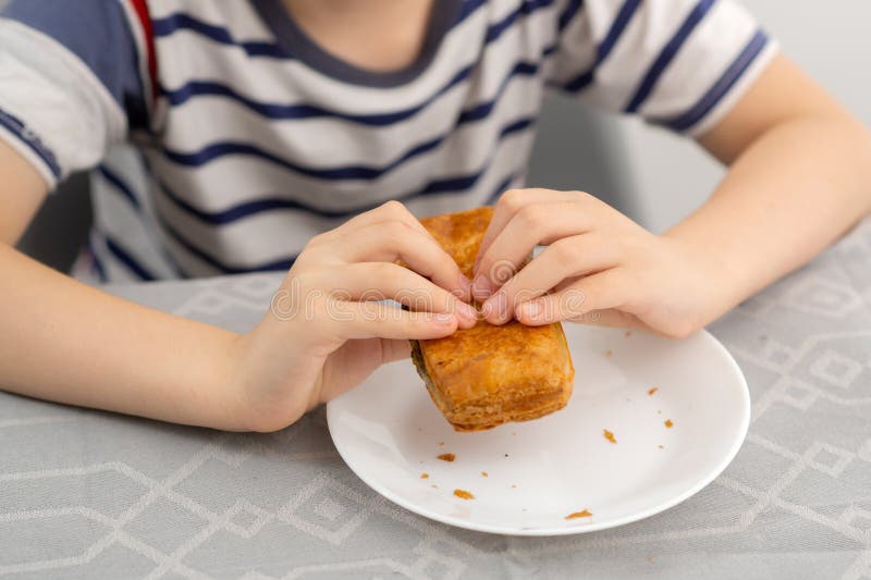 Anticipazione culinaria : un ragazzo che tiene con impazienza una pasta di pasta al forno pronta a assaporare su un piatto bianco immagini stock libere da diritti