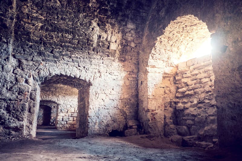 Antico seminterrato di pietra con archi. Il sole si spezza attraverso la finestra. piano terra fotografie stock