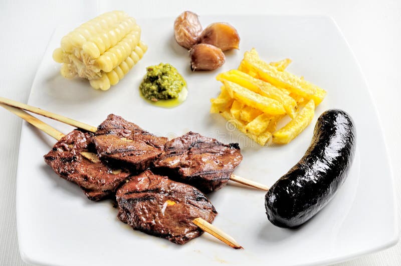 Anticuchos, cuisine péruvienne, brochettes de viande grillées de coeur de boeuf avec la pomme vapeur et maïs blanc images libres de droits Anticuchos, cuisine péruvienne, brochettes de viande grillées de coeur de boeuf avec la pomme vapeur et maïs blanc images libres de droits