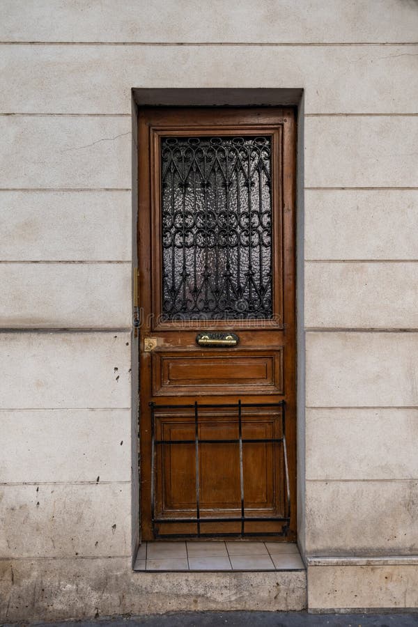 Antieke deur met zwarte metaalgrating van de oude bouw in Parijs Frankrijk Uitstekende houten deuropening en vuile steenmuur van royalty-vrije stock fotografie Antieke deur met zwarte metaalgrating van de oude bouw in Parijs Frankrijk Uitstekende houten deuropening en vuile steenmuur van royalty-vrije stock fotografie