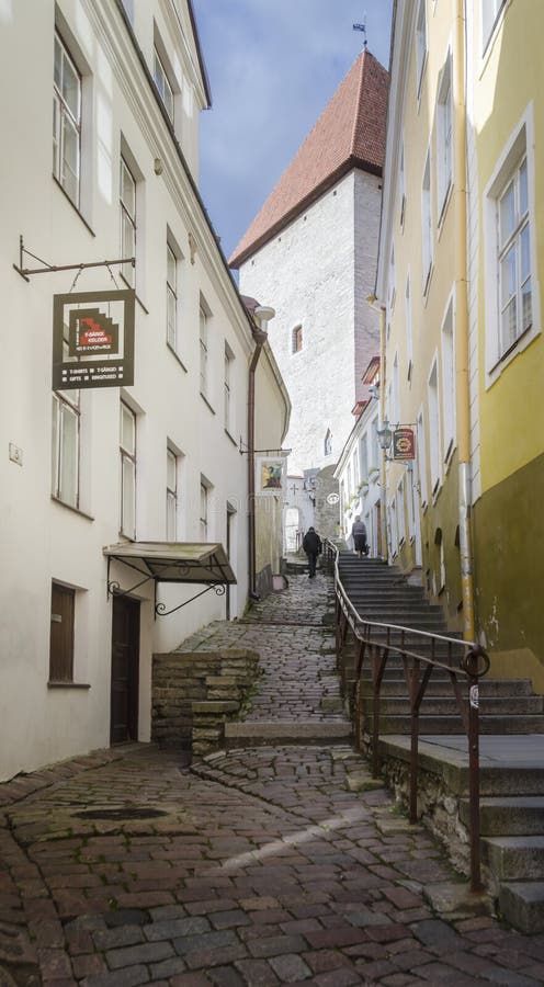 View looking uphill at people walking up a steep alley with cobbled stones and steps, in the city of Tallinn, Estonia. View looking uphill at people walking up a steep alley with cobbled stones and steps, in the city of Tallinn, Estonia