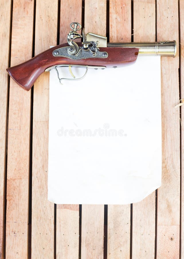 Antike Feuerwaffen mit leerem Papier auf dem Bretterboden lizenzfreie stockfotos Antike Feuerwaffen mit leerem Papier auf dem Bretterboden lizenzfreie stockfotos