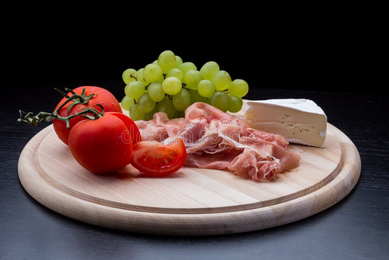 Antipasti con il prosciutto di Parma, formaggio, uva, pomodori immagine stock