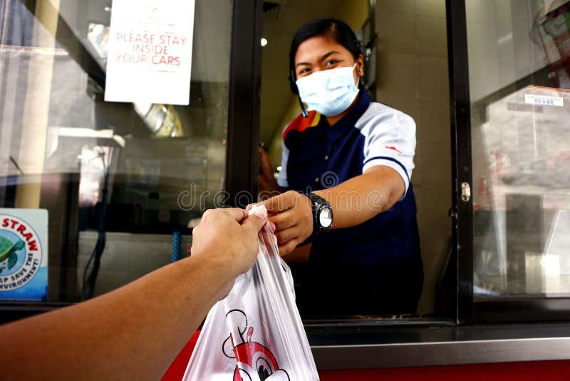 Fast food employee gives a food order at the drive thru window during the Covid 19 virus outbreak