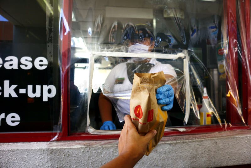 Fast food employee gives a food order at the drive thru window during the Covid 19 virus outbreak