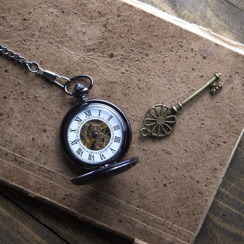Antique book and pocket watch on grunge wooden table