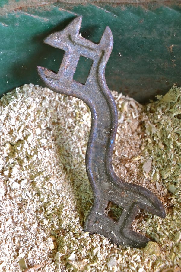 Antique box wrench laying in a pile of sawdust