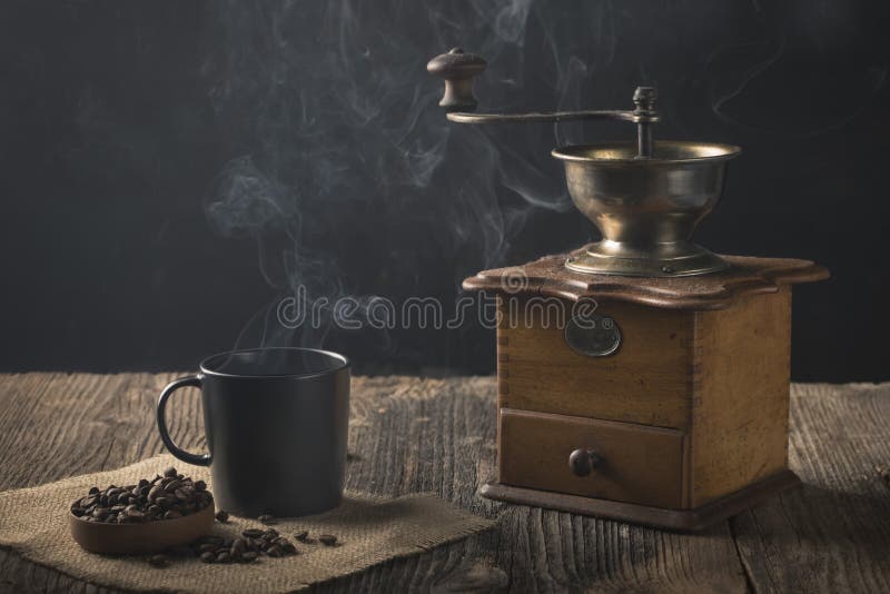 Antique coffee grinder with steaming coffee, and coffee beans royalty free stock photos Antique coffee grinder with steaming coffee, and coffee beans royalty free stock photos