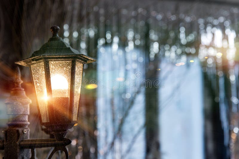 Antique frosty lamppost with orange light on the street close up on the background of the window in shining Christmas. Decorations sequins. Vintage glass light