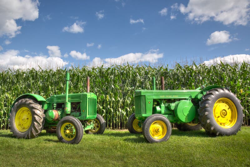Antique Vintage Green John Deere Tractors in front of a corn field with a blue sky. royalty free stock photography Antique Vintage Green John Deere Tractors in front of a corn field with a blue sky. royalty free stock photography