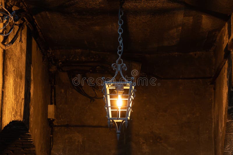An antique lantern illuminates a narrow street in the Old Town of Nice, France. Shadows fall on the stone walls, creating an stock image