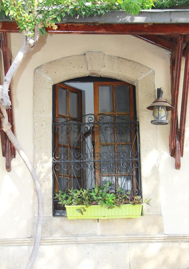 Antique Windows with Metal Bars in Wooden Frames on the Facade of the