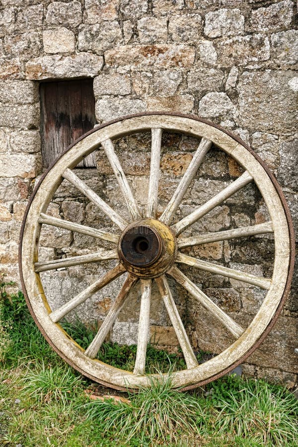 Antique Wood Wagon Wheel against Old Stone Wall