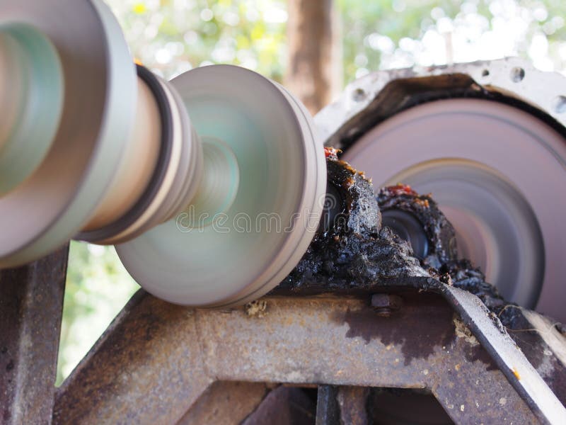 Close up of a metal steel drive shaft of a water pump on a large size ball bearing support and universal joint with dark dirty grease on running working showing motion blur on the machine moving parts. Close up of a metal steel drive shaft of a water pump on a large size ball bearing support and universal joint with dark dirty grease on running working showing motion blur on the machine moving parts