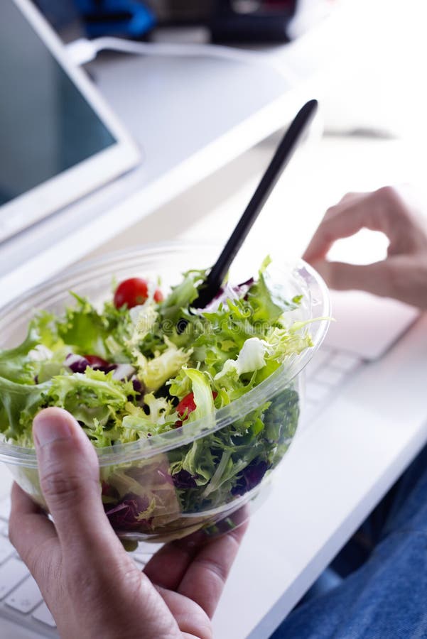 Antrop?fago joven una ensalada en la oficina fotos de archivo libres de regalías Antrop?fago joven una ensalada en la oficina fotos de archivo libres de regalías