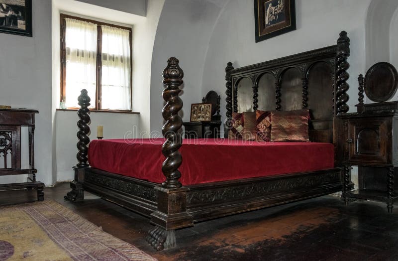 Bran, Transylvania region, Romania - June 10, 2018: Interior of the bedroom of the vampire Count Dracula in the medieval castle of Bran in Romania. Antique wooden bed with a red bedspread. The legendary tourist attraction of Eastern Europe. Bran, Transylvania region, Romania - June 10, 2018: Interior of the bedroom of the vampire Count Dracula in the medieval castle of Bran in Romania. Antique wooden bed with a red bedspread. The legendary tourist attraction of Eastern Europe