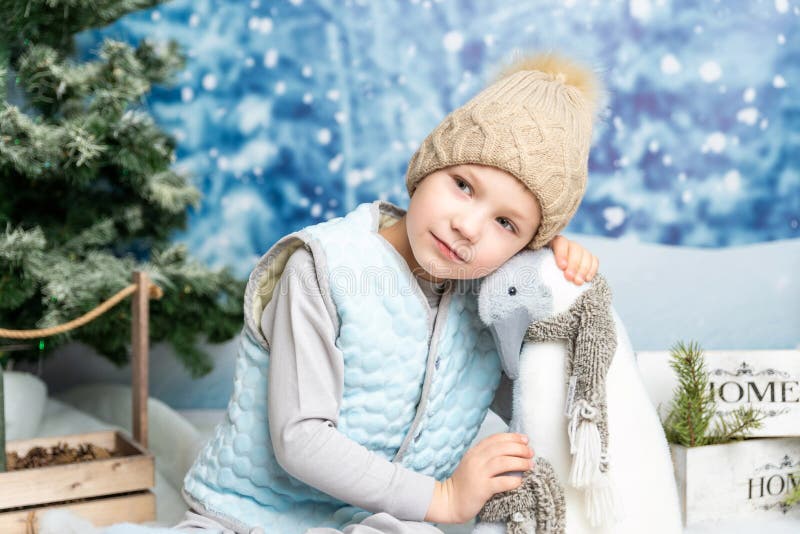 Anul nou și de Crăciun. băiețelul care stă cu pinguini cu jucării moi pe fond decorat pe timp de iarnă royalty free stock image