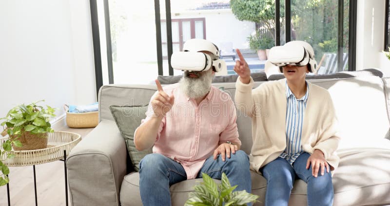 Använda VR-headset högt par som sitter på soffan och interagerar med den virtuella världen arkivfilmer