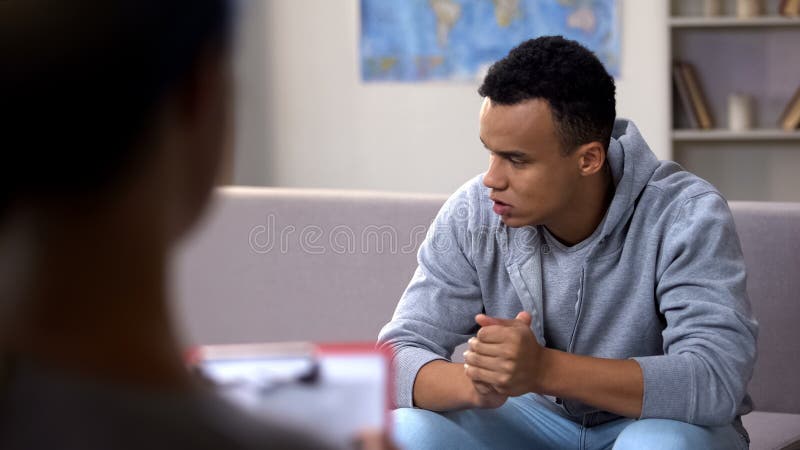 Anxious drug addicted black teenager suffering withdrawal, psychotherapy session, stock photo