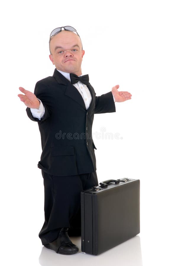 Little businessman, dwarf in a formal suit with bow tie next to suitcase, studio shot, white background. Little businessman, dwarf in a formal suit with bow tie next to suitcase, studio shot, white background