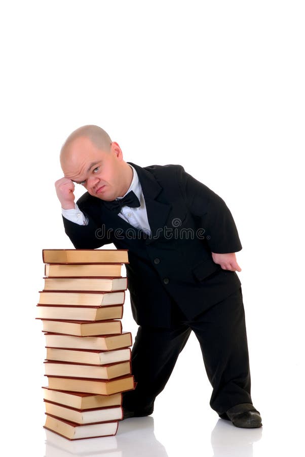 Little man, dwarf teacher in a formal suit leaning on stack of books, encyclopedia, studio shot, white background. Little man, dwarf teacher in a formal suit leaning on stack of books, encyclopedia, studio shot, white background