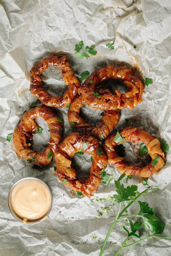 Crispy deep-fried onion rings on parchment paper. Crispy deep-fried onion rings on parchment paper