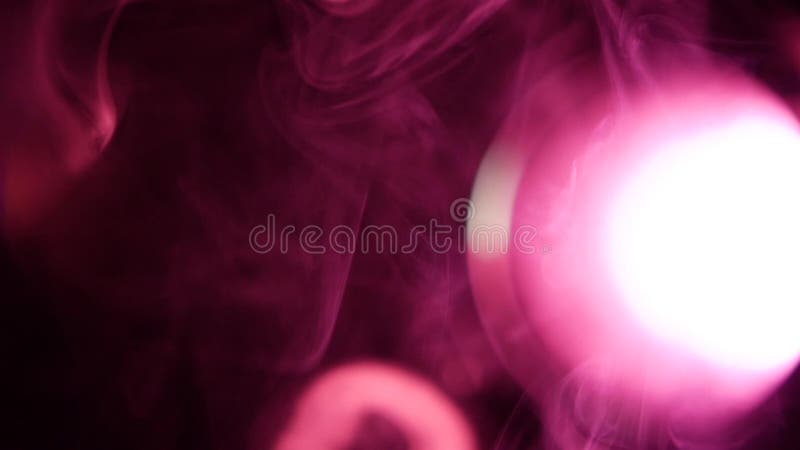 Anéis do fumo branco com iluminação roxa, no preto