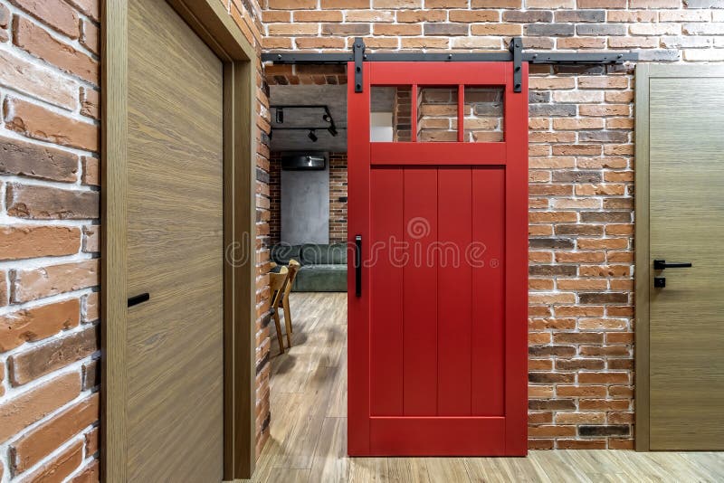 Apartment interior with sliding red door and clay red brick wall decoration