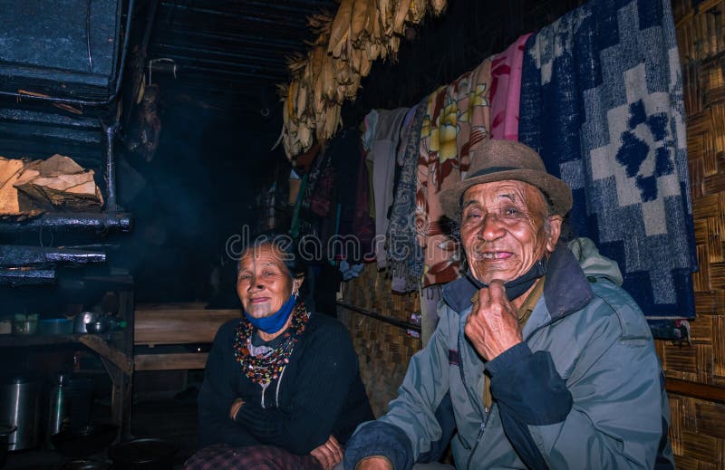 Apatani tribal couple at their home near fire place cooking food at evening from flat angle