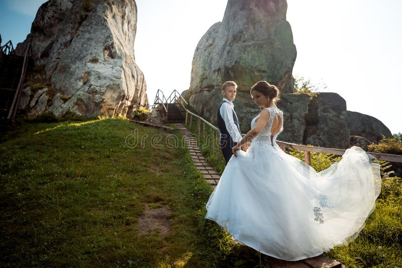 Apenas pareja casada feliz joven atractiva en las escaleras de madera en las montañas La novia encantadora está jugando con fotos de archivo libres de regalías Apenas pareja casada feliz joven atractiva en las escaleras de madera en las montañas La novia encantadora está jugando con fotos de archivo libres de regalías