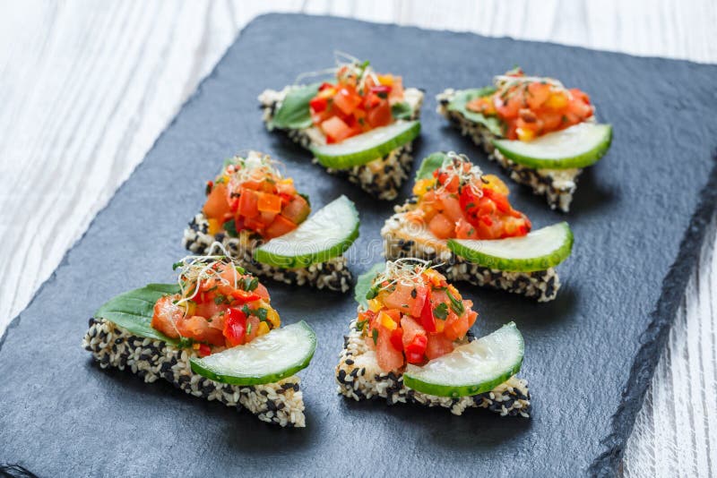 Aperitif Canape mit gehacktem Gemüse und indischem Sesam auf Steinschieferhintergrundabschluß oben stockfotos