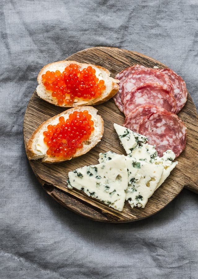 Aperitivos deliciosos para o vinho - salsicha fumado, sanduíches vermelhos do queijo creme do caviar, queijo azul em uma placa de fotos de stock royalty free Aperitivos deliciosos para o vinho - salsicha fumado, sanduíches vermelhos do queijo creme do caviar, queijo azul em uma placa de fotos de stock royalty free
