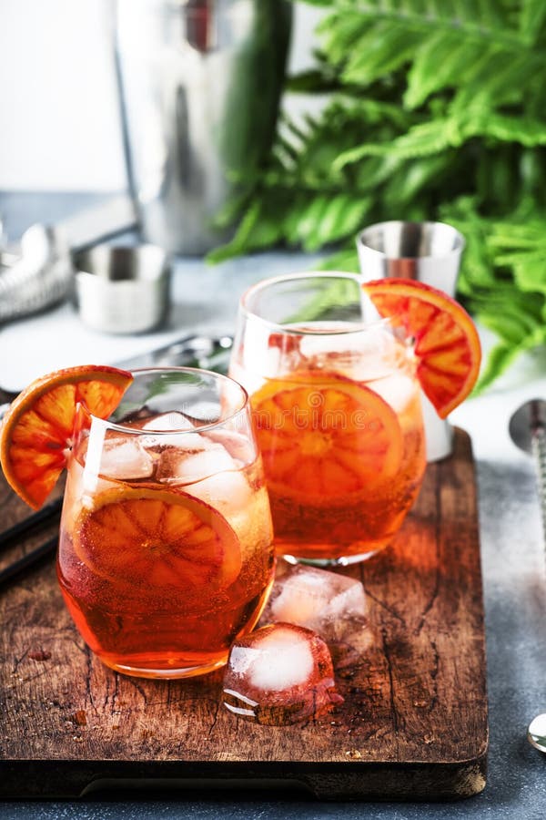 Aperol spritz cocktail in wine glass with sparkling wine, liqueur, ice cubes and red orange - summer Italian low alcohol cold