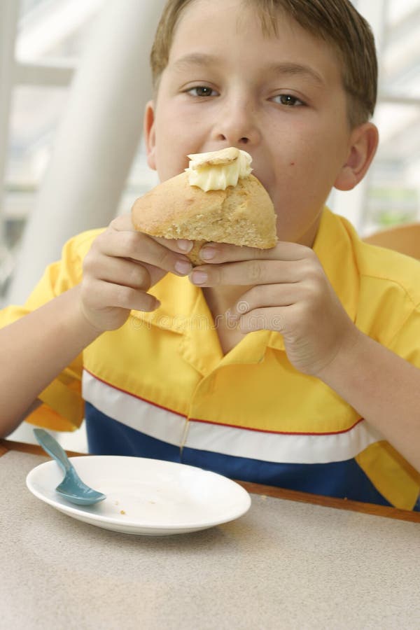 Apetite com fome: Criança que come um queque cozido delicioso imagem de stock Apetite com fome: Criança que come um queque cozido delicioso imagem de stock