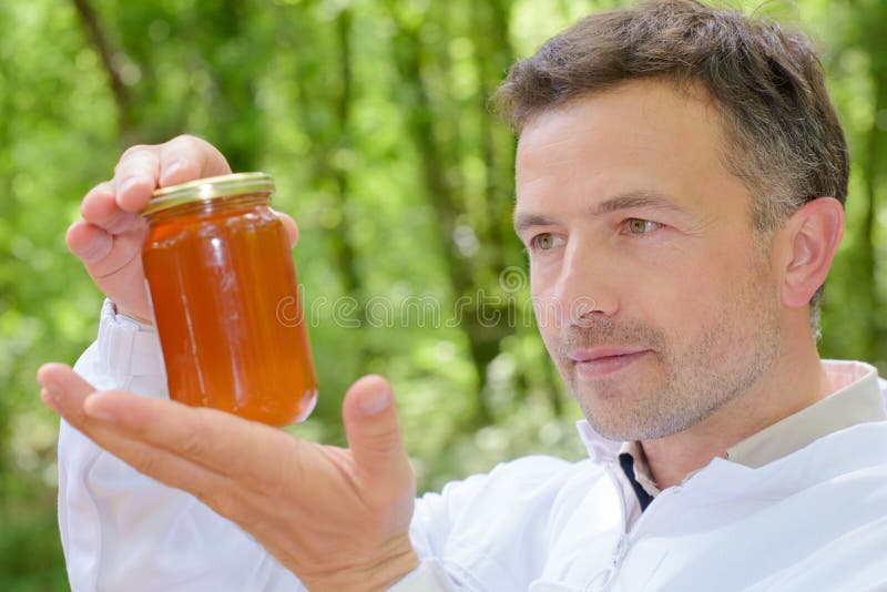 Apiculteur tenant le miel de pot image stock Apiculteur tenant le miel de pot image stock