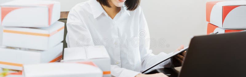 Apoyos sonrientes hermosos de la mujer usando el ordenador portátil que comprueba la orden para saber si hay cliente y la entrega imágenes de archivo libres de regalías