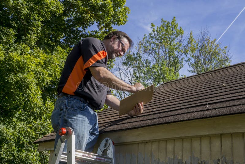 Contractor using a clipboard to figure our repiar cost for hail damaged roof. Contractor using a clipboard to figure our repiar cost for hail damaged roof.