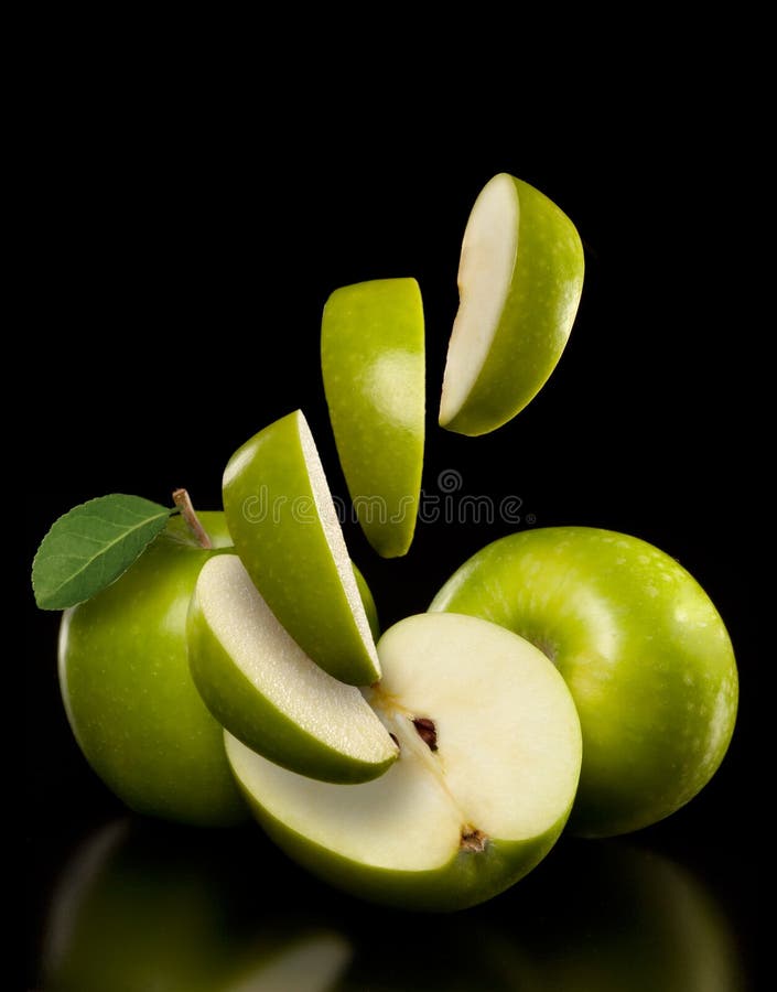 Green apples and apple slices on a black background. Green apples and apple slices on a black background.