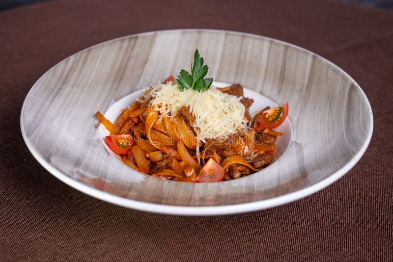 Appetizing pasta with beef, tomatoes and hard cheese in a plate. royalty free stock photos